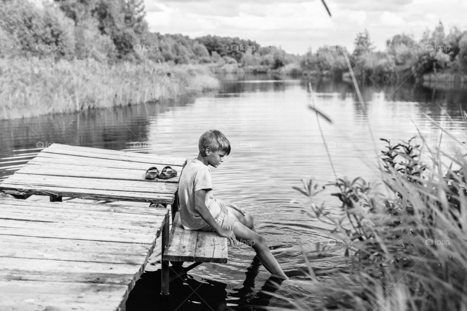 Boy sitting watching reflection in the water