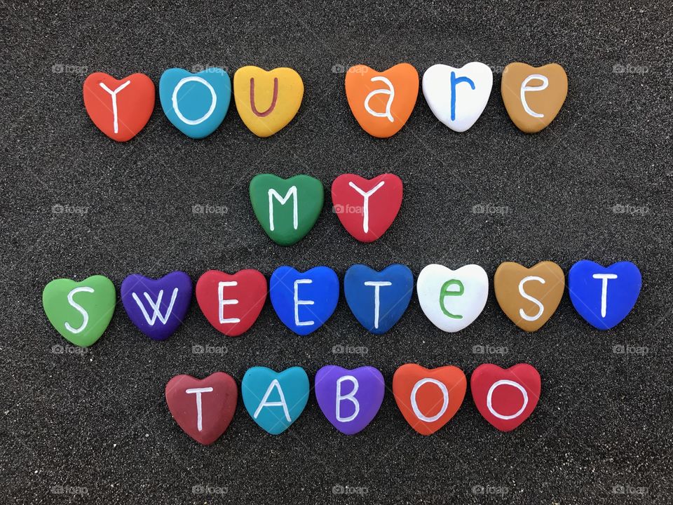 You are my sweetest taboo, love declaration with colored heart stones over black volcanic sand
