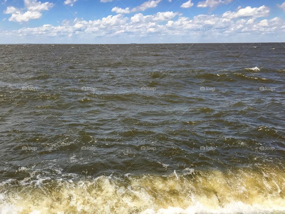 The brackish waters of Lake Pontchartrain on a billowy cloud filled day.