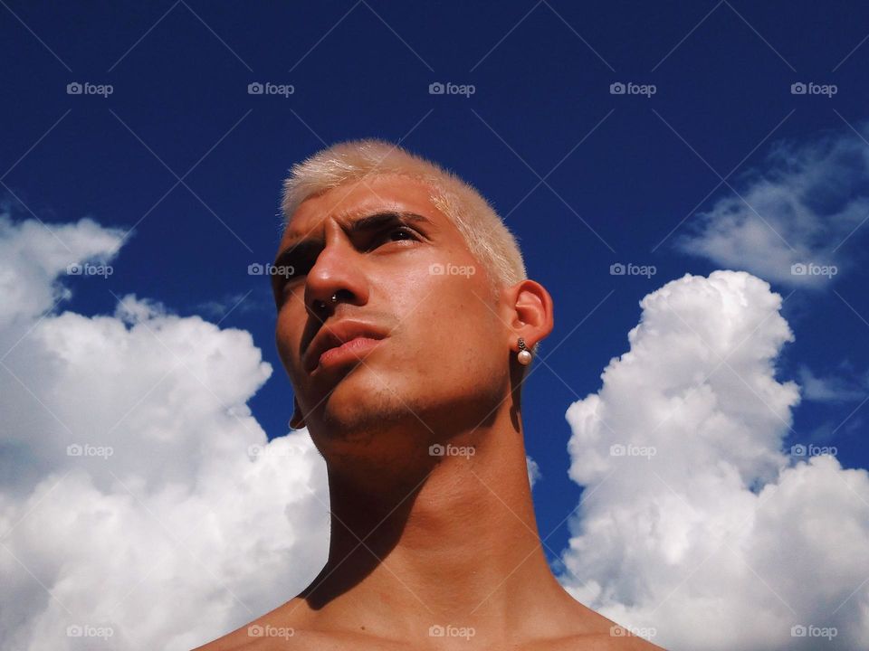 a Self Portrait, or selfie, of a Younger me, with a pearl earing, nose ring and blonde hair. I love the color of the sky and the clouds behind.