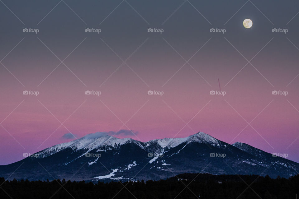 Snow covered mountain range and moon