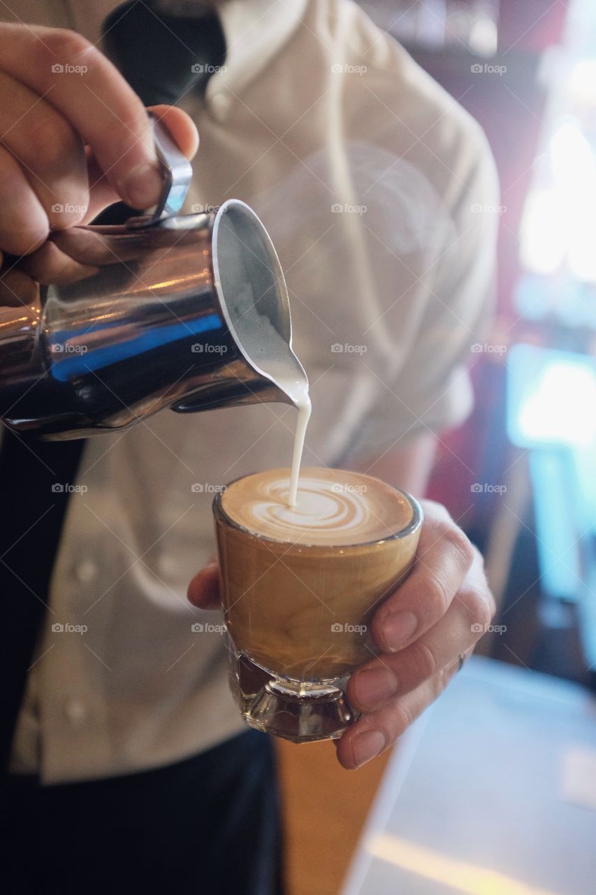 Person pouring milk into the coffee