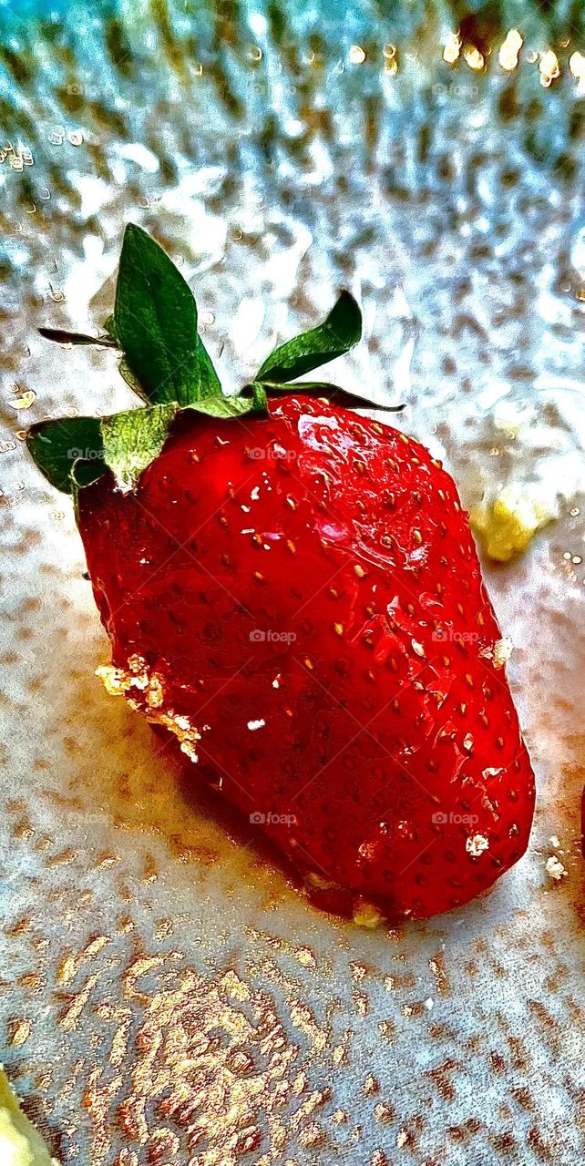Ripe strawberries lying on a plate of bright red color with shiny skin, strewn with tiny yellow seeds.