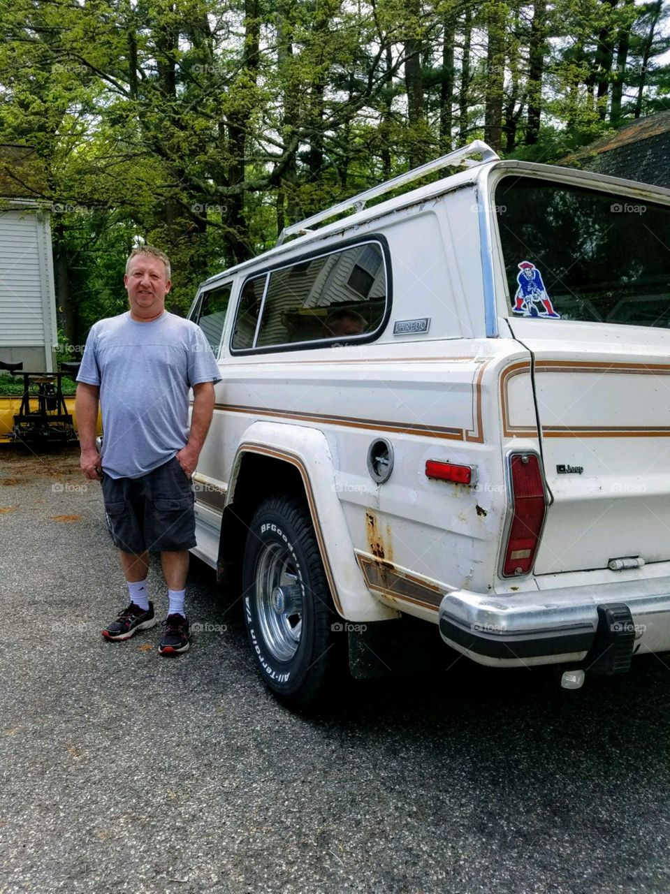 Man standing with his classic Jeep that's being restored by him. It's an original white color & it runs great and drives it all the time.