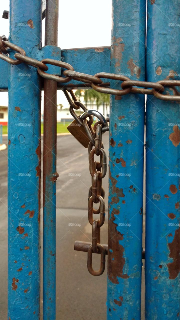 Portão de ferro com corrente e cadeado.