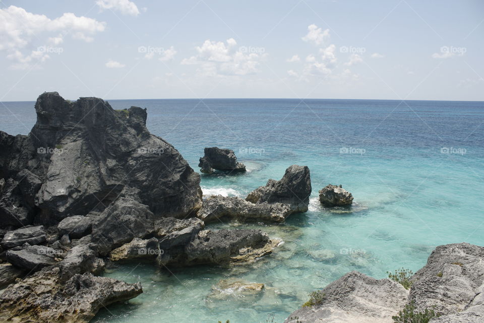 Aquamarine waters surround rocky cliffs on this island beach. No people, just nature.