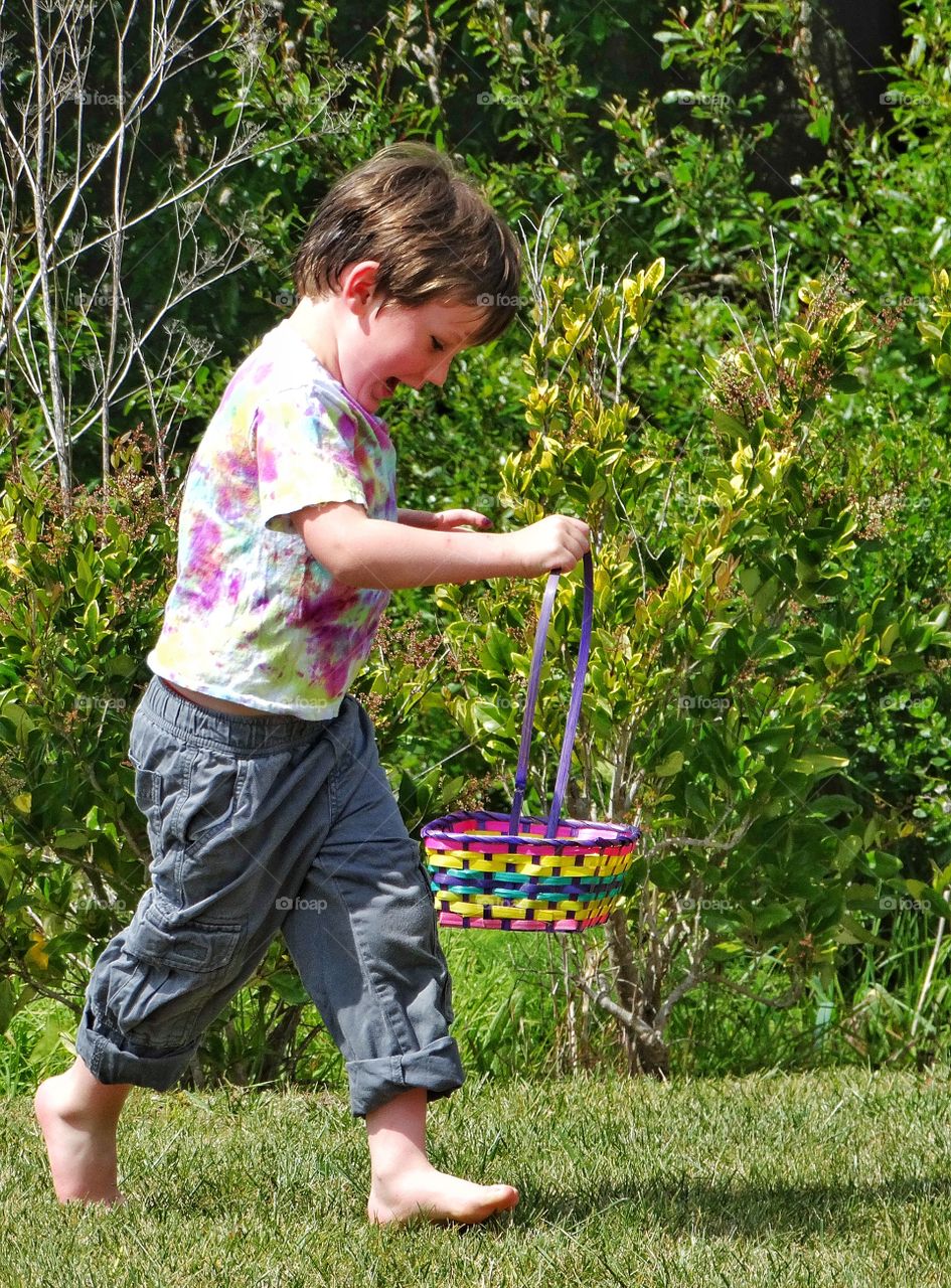 Easter Egg Hunt. Young Boy With Basket Hunting For Easter Eggs
