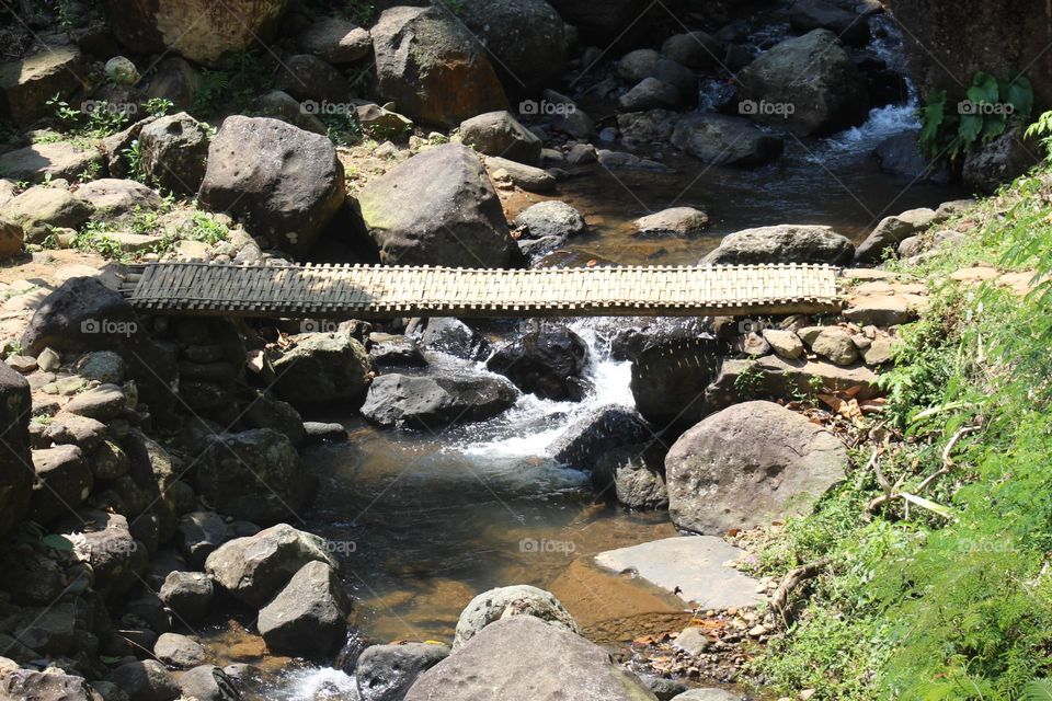 bamboo bridge over a rocky river