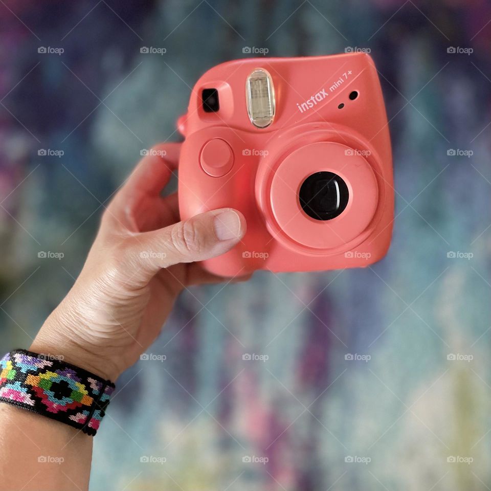 Woman’s hand holding Instax instant camera, making memories, instant camera from Fujifilm, new age instant cameras, cute instant camera, pink Instax camera 