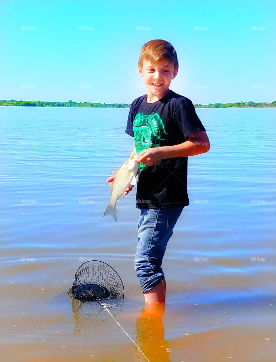 Boy holding fish in lake with net