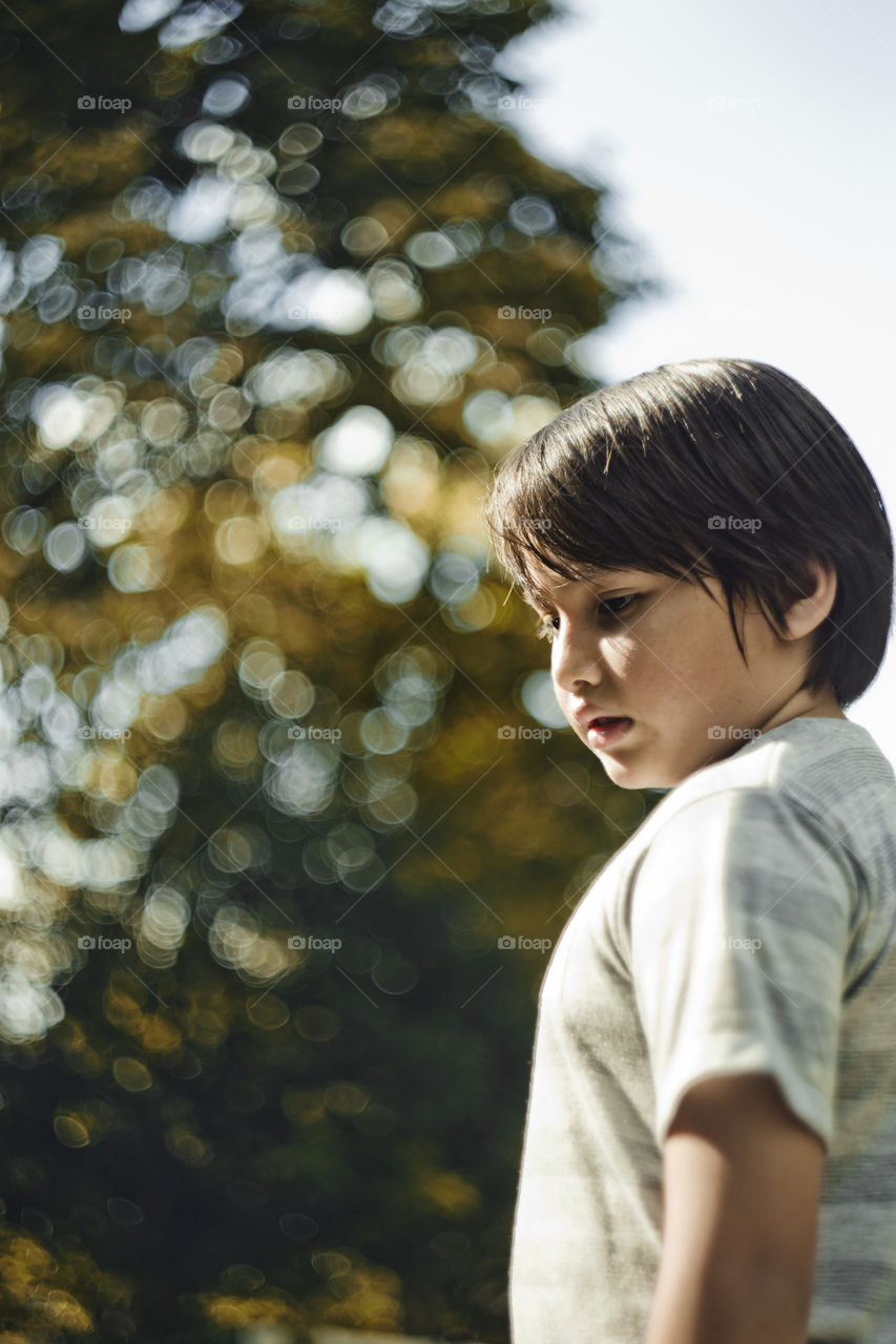 outdoor portrait of happy young eurasian boy on a blurry out of focus bokeh foliage background