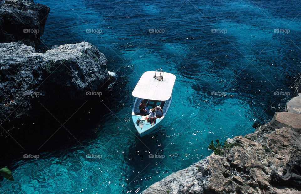 Boat floats off the rocky coast in Montego bay, Jamaica.