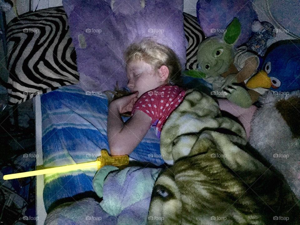 Girl sleeping with Yoda and light saber