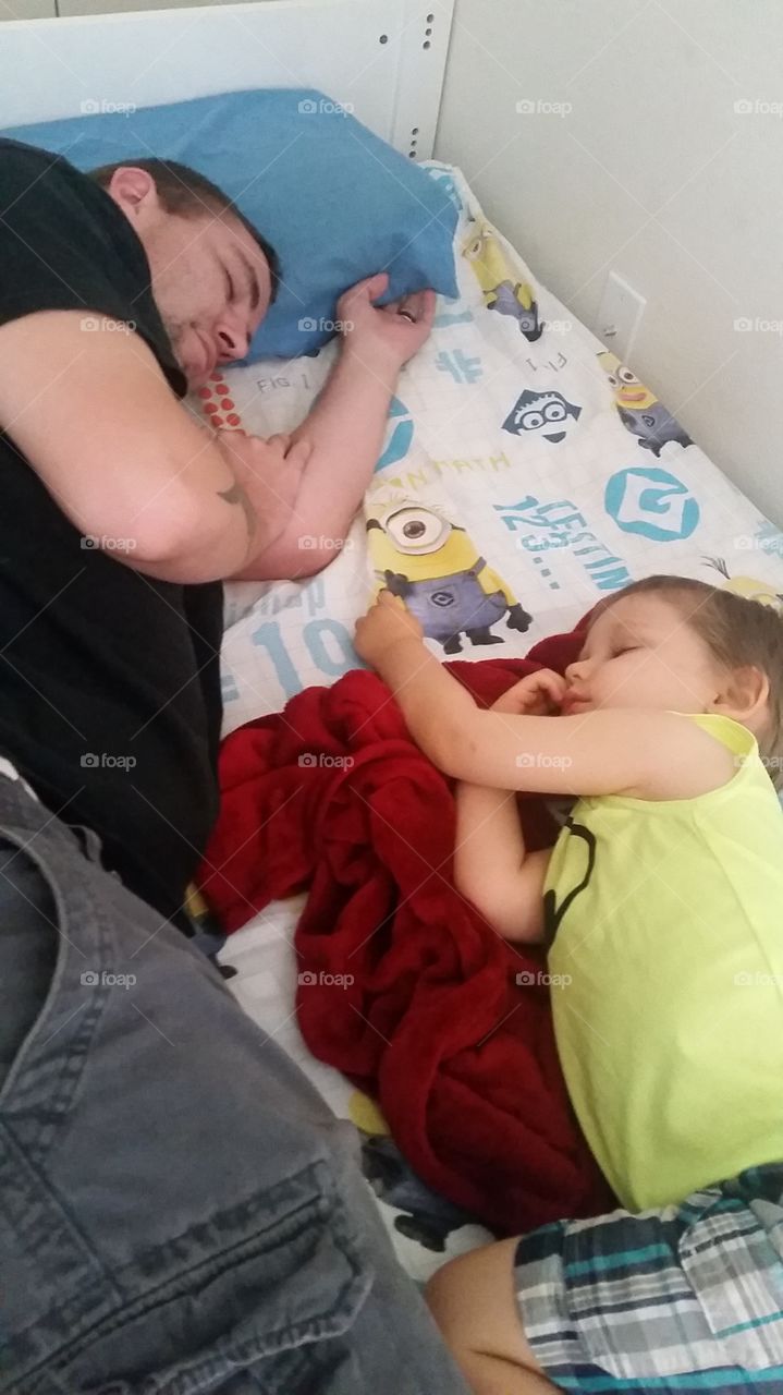 Elevated view of father and son sleeping on bed
