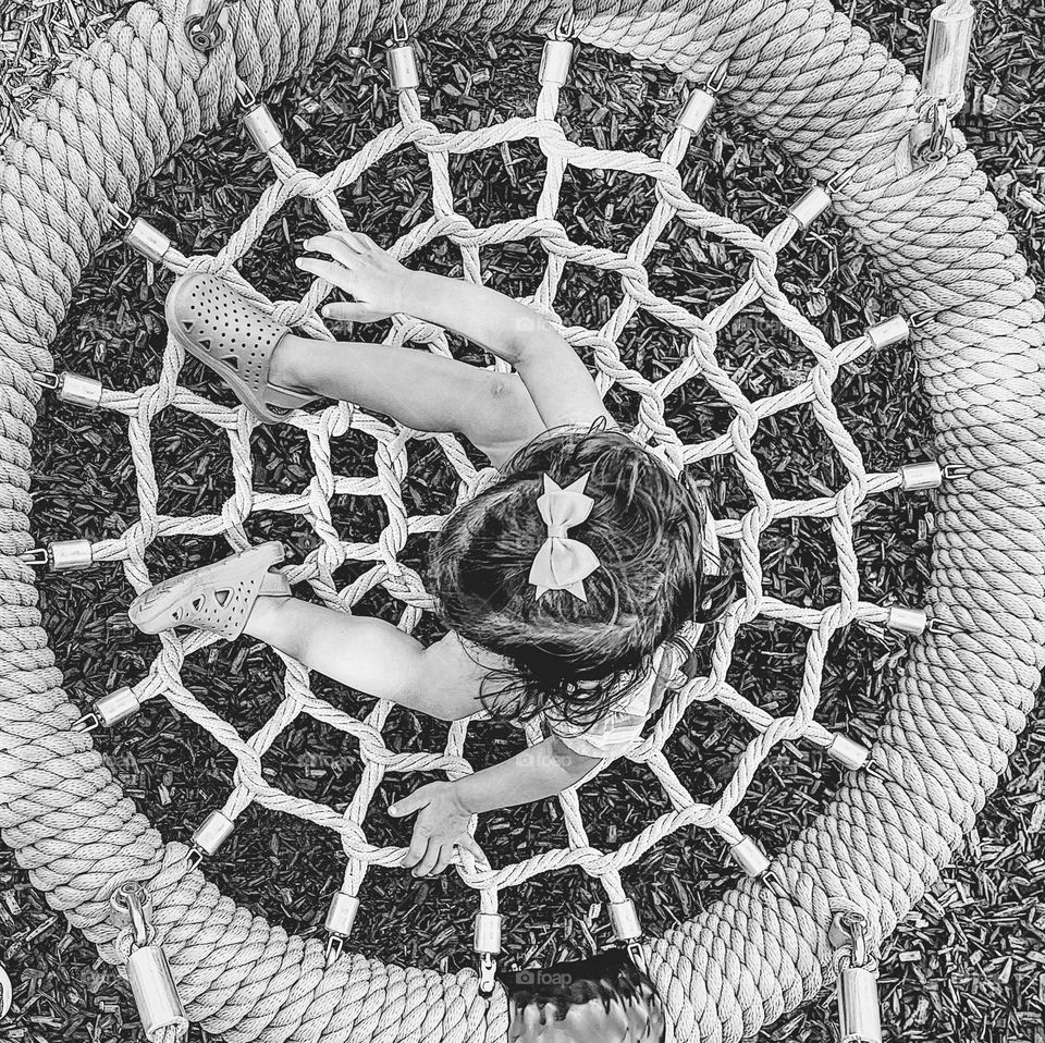 Toddler girl swings on a rope swing, toddler at the park, black and white child portraits, swinging at the park, having fun in monochrome