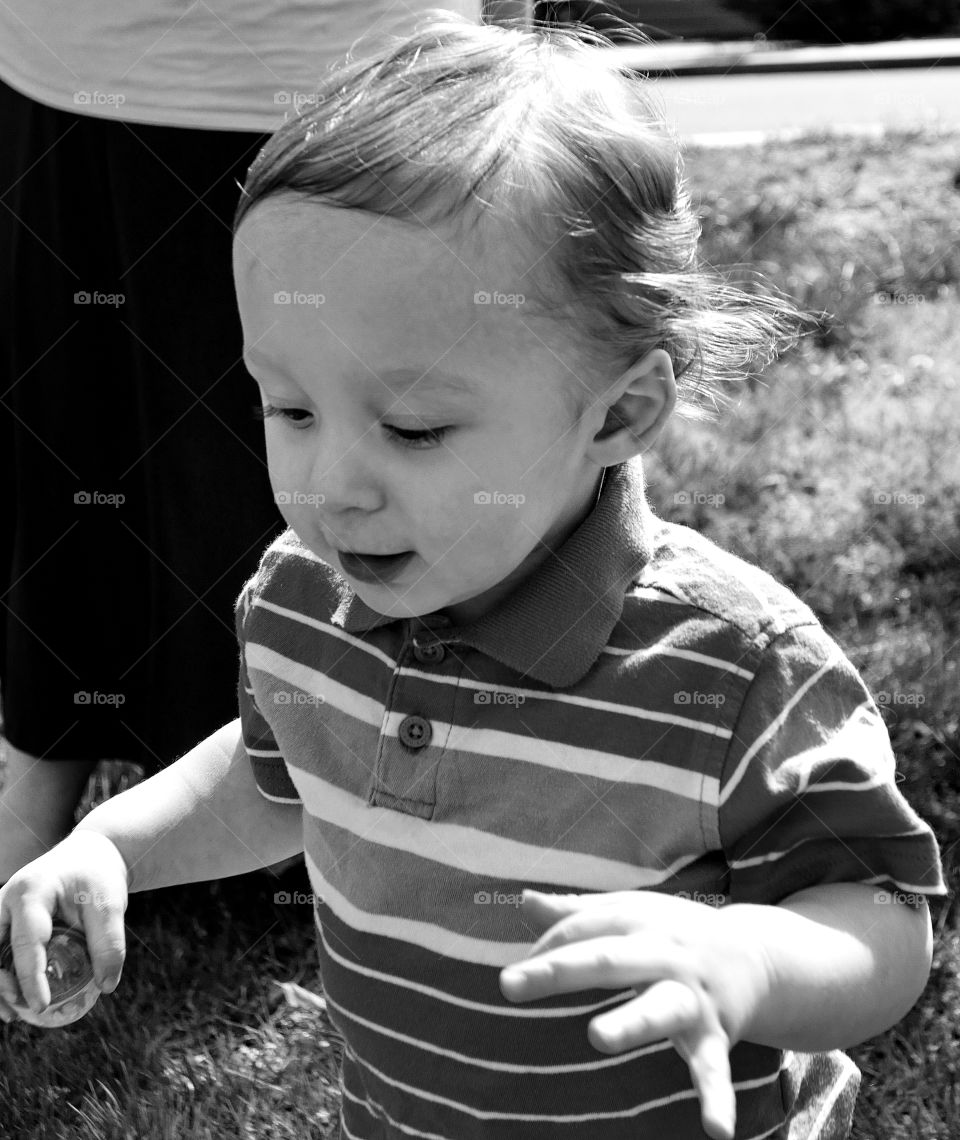 An adorable little toddler boy expresses excitement while on the hunt for Easter eggs. 