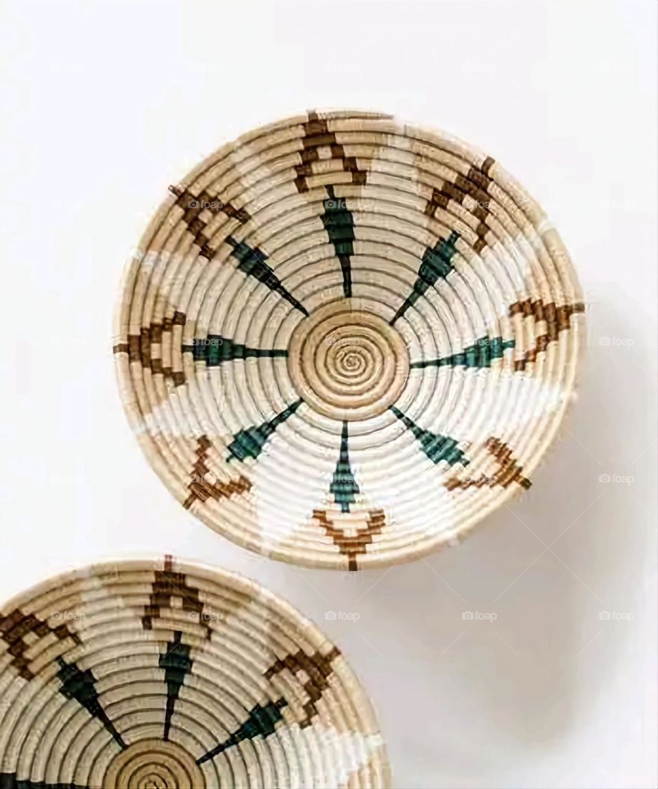 The image shows a group of hand -made dishes of wicker, decorated with colored embroideries with beautiful floral shapes, and is elegantly displayed in a warm corner that combines heritage and beauty, which gives the place an artistic spirit and attr