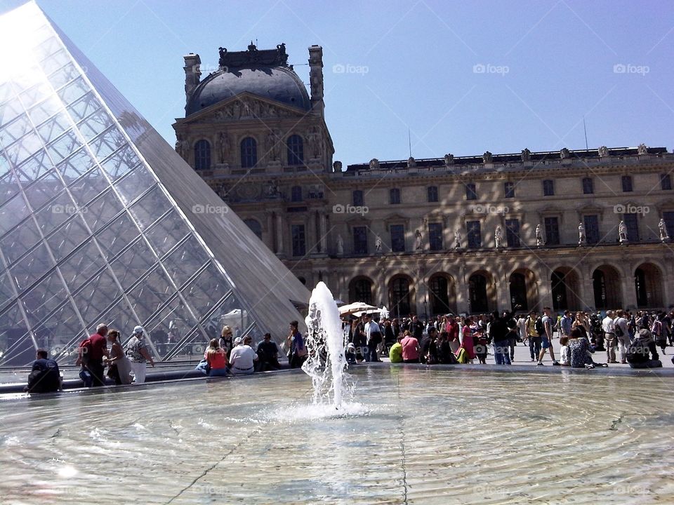 It is the Louvre museum in Paris. I have focused part of the museum and part of the building that is next to it. There is also a fountain.