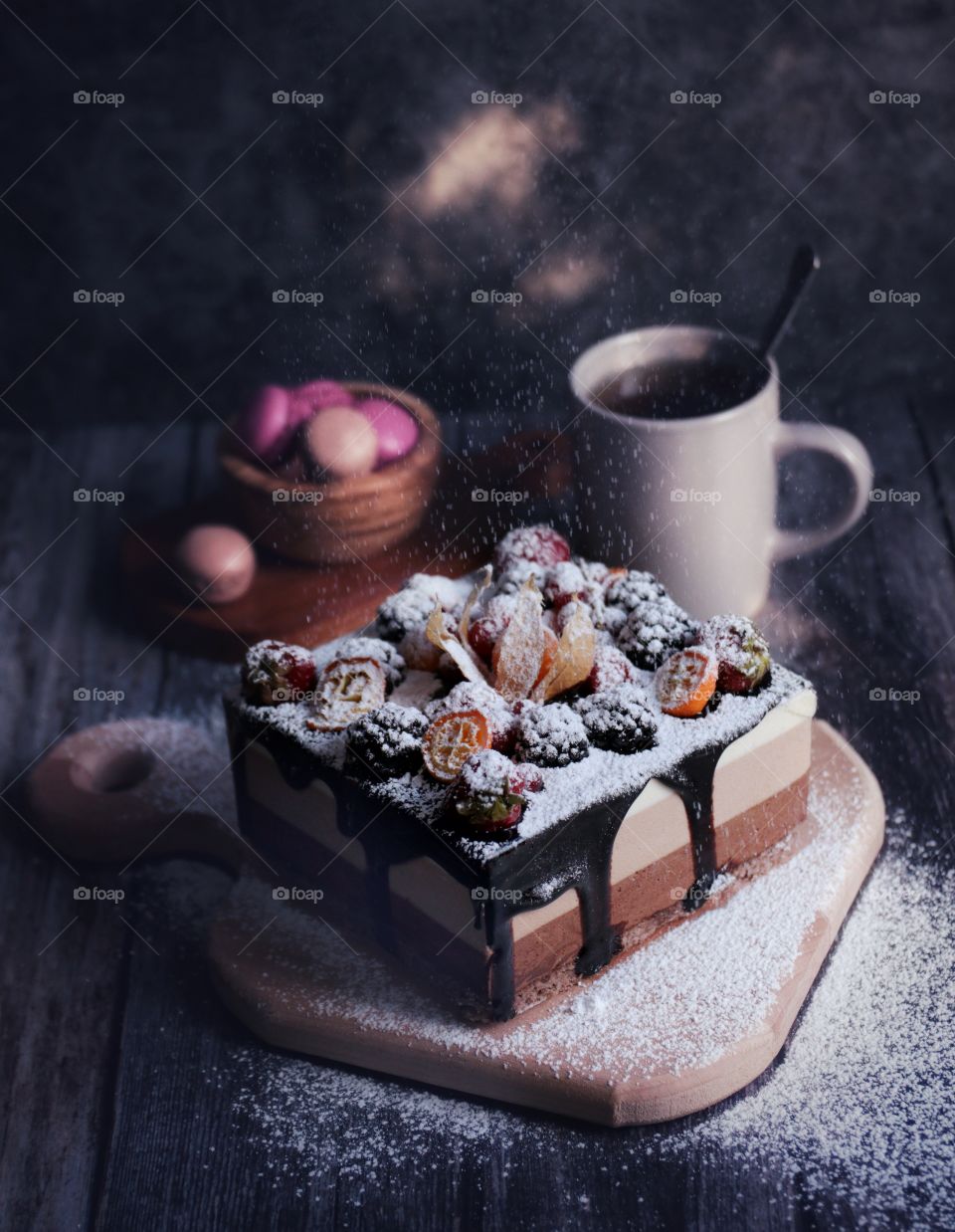 Three chocolate cake with berries and a cup of tea