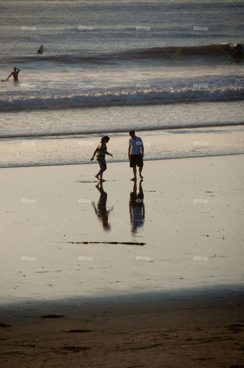 Man and woman walking on the beach at sunset