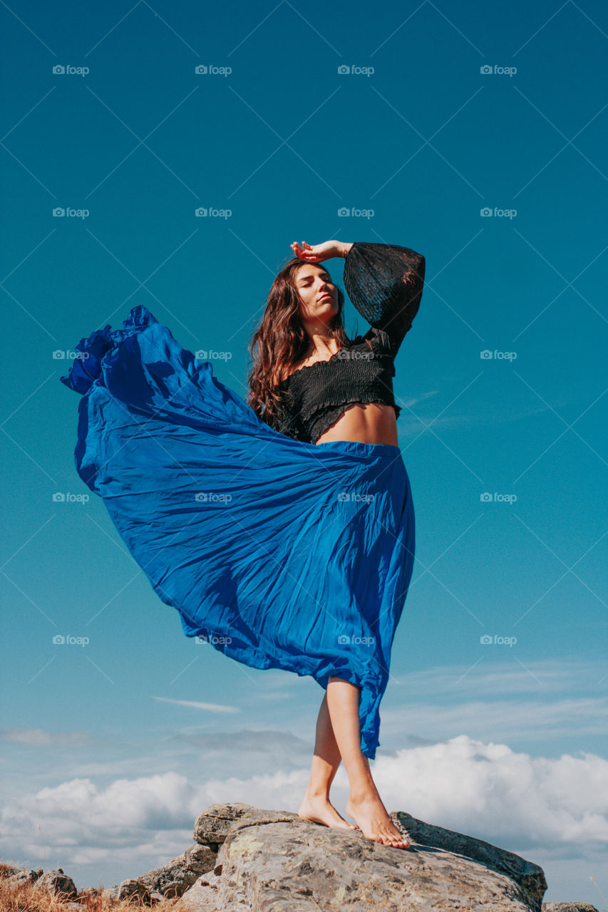 standing on rocks with a beautiful blue skirt