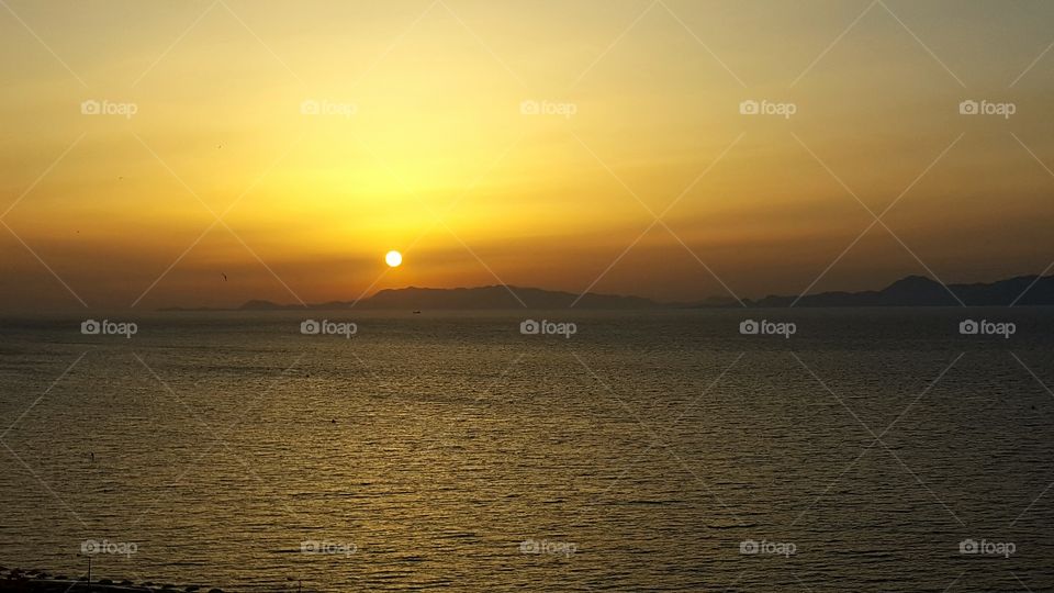 Sun sets on Rhodes behind Turkish mountains