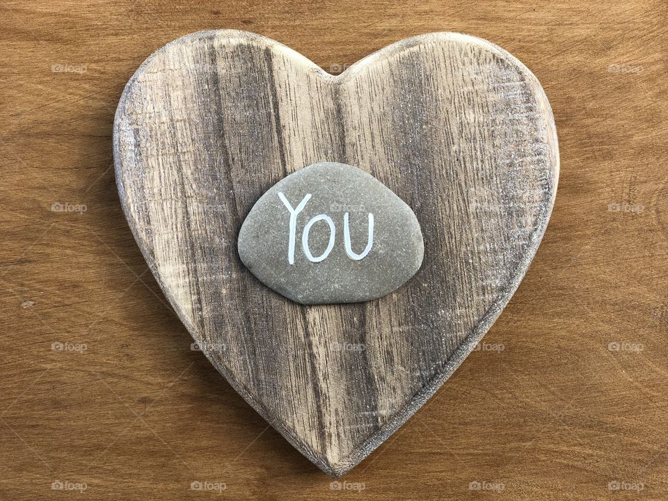 Love you message with a carved stone over a wooden heart