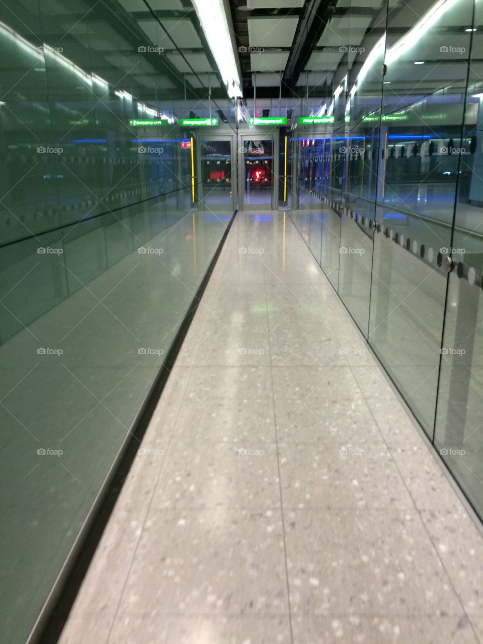Long green glass security corridor at airport