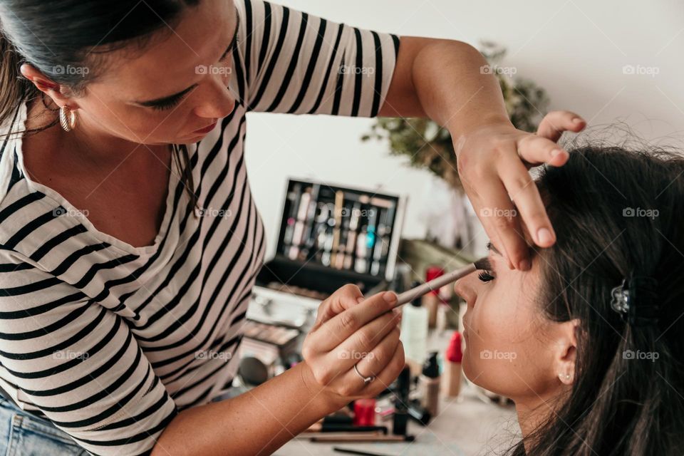 Beautician doing make-up on young woman in beauty salon