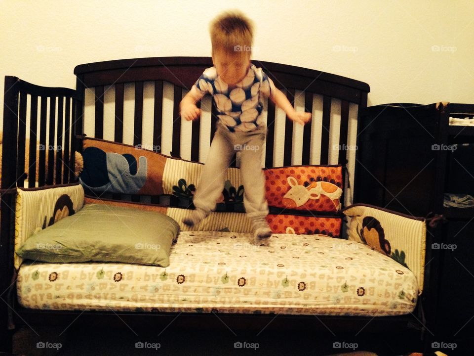 Happy toddler jumping in crib 