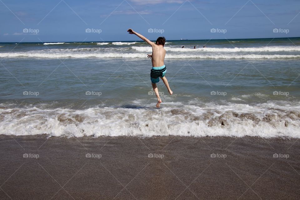 Boy jumping over waves in Atlantic Ocean 