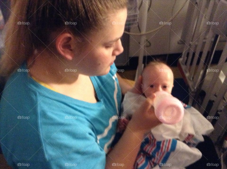 Older sister feeding sister with Down syndrome after open heart surgery