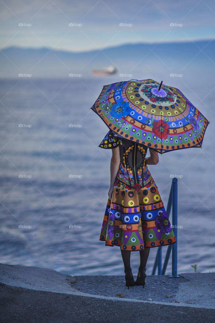Umbrella and a girl. beutiful colors against blue sea