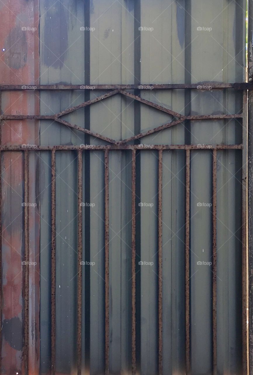 Wrought iron gate against metal fencing symmetrical lines 