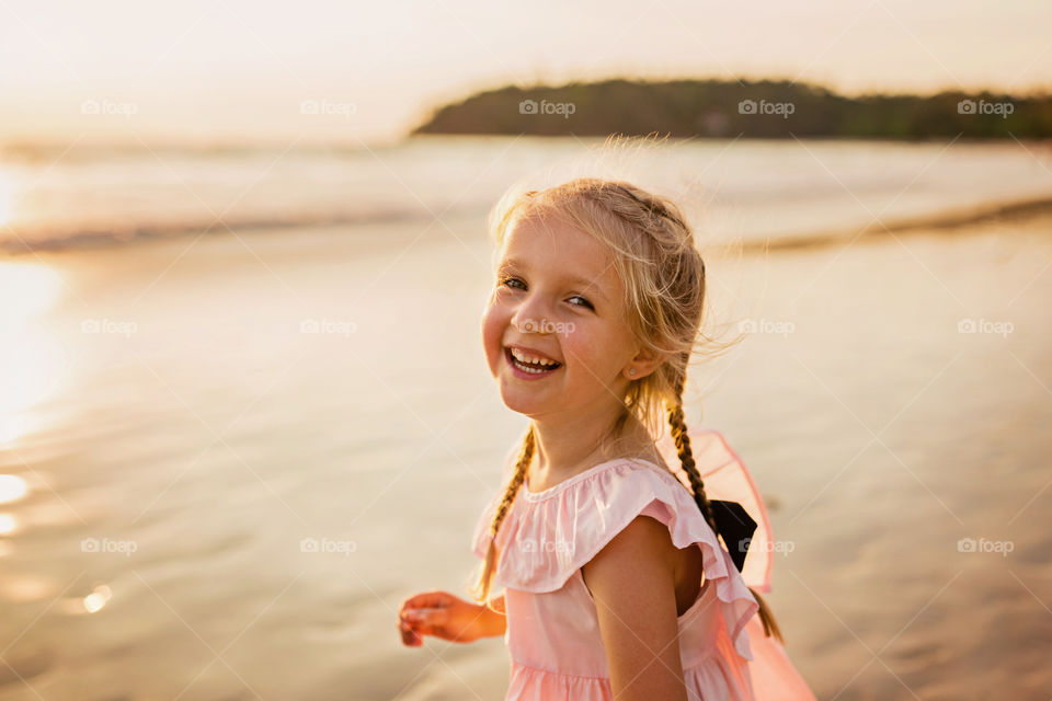 Portrait of cute little girl with blonde hair on the beach 