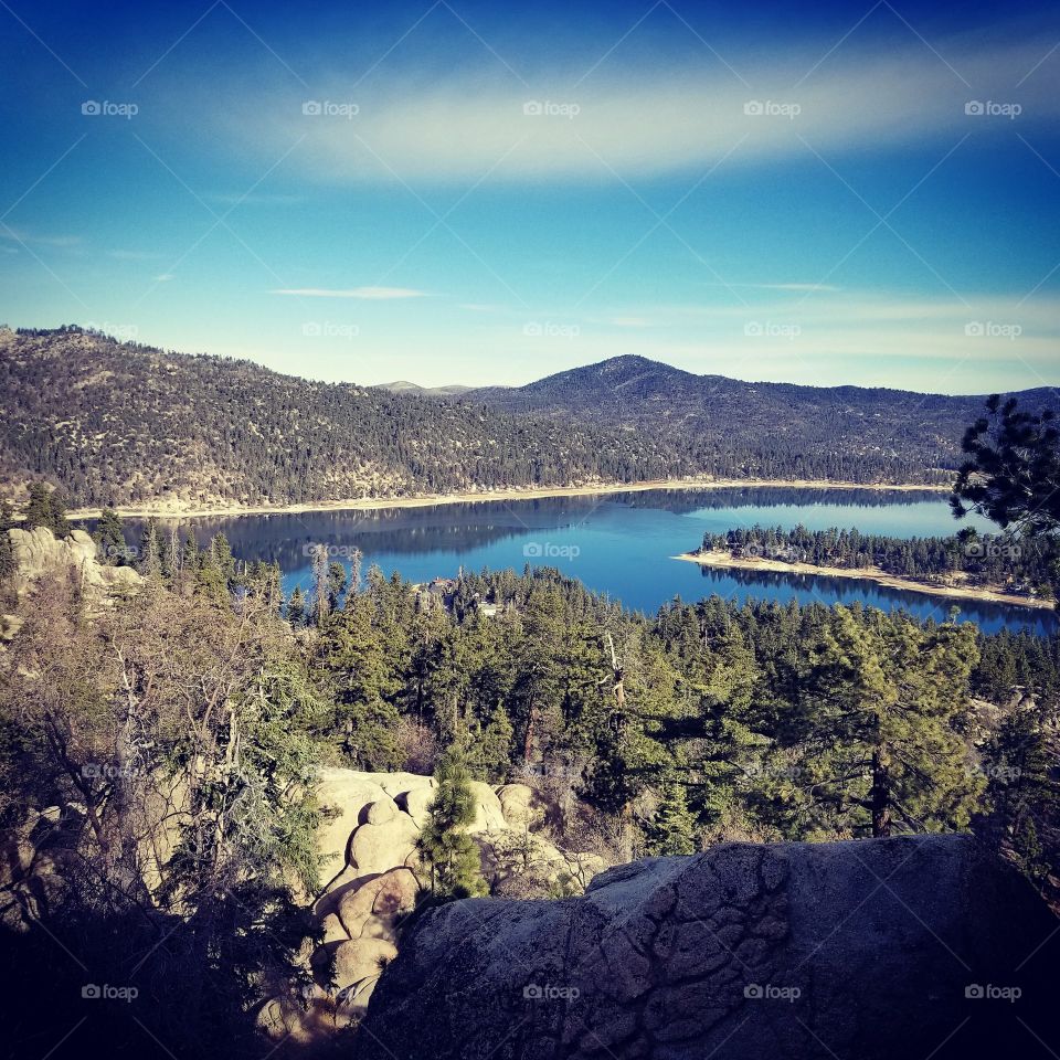Hanging from a cliff, I took this photo of a lake and forest in Big Ben, CA