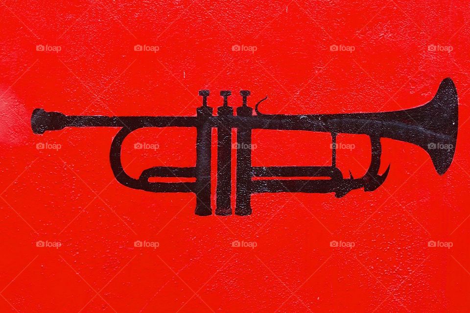 A closeup portion of an outdoor mural in Miami, Florida showing a black trumpet on a red background.
