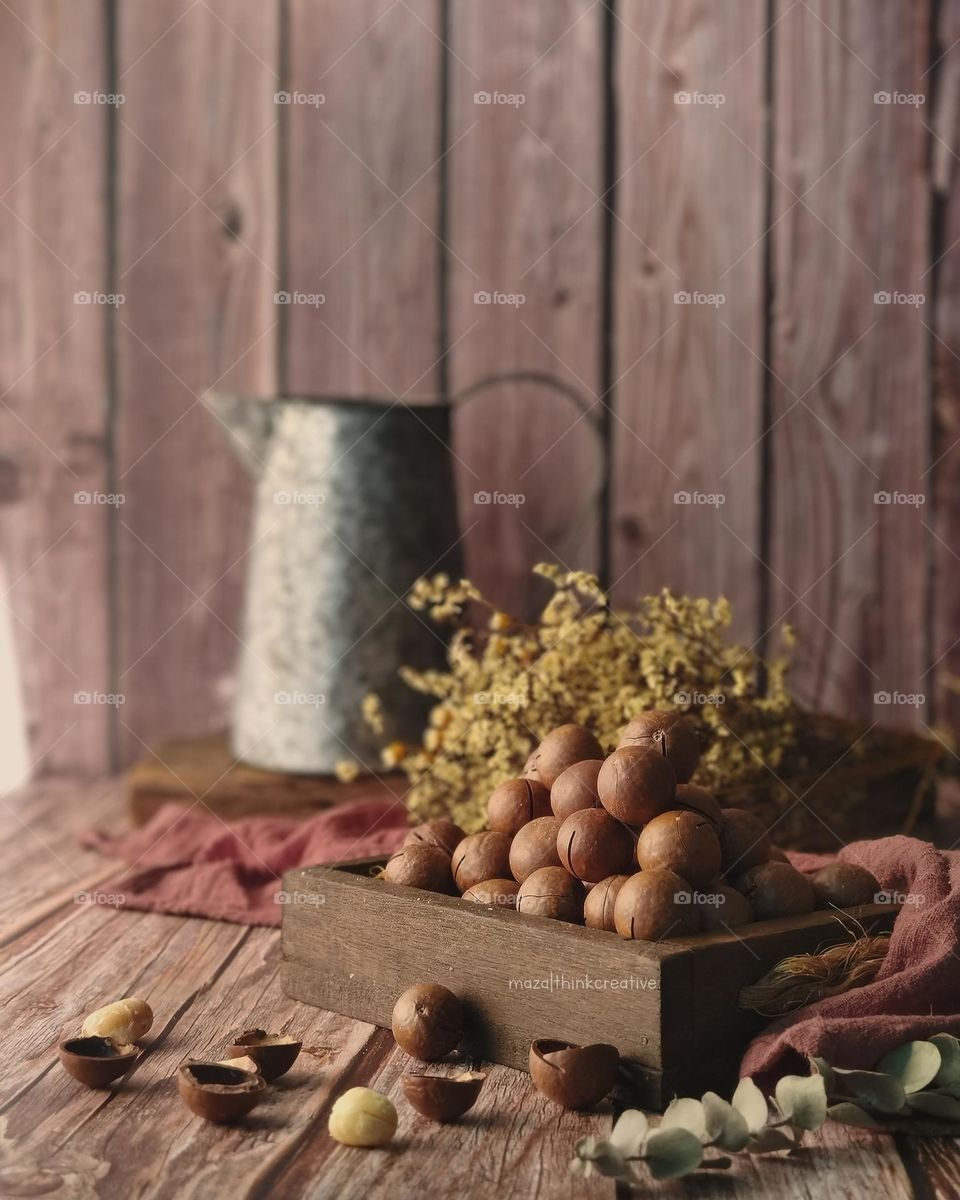 Macadamia nuts with shells in a wooden box with vintage mood