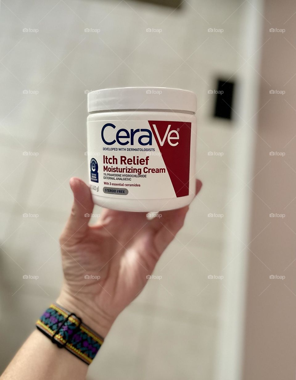 Woman’s hand holding Cera Ve cream bottle, products to help eczema, healing your skin with cream 