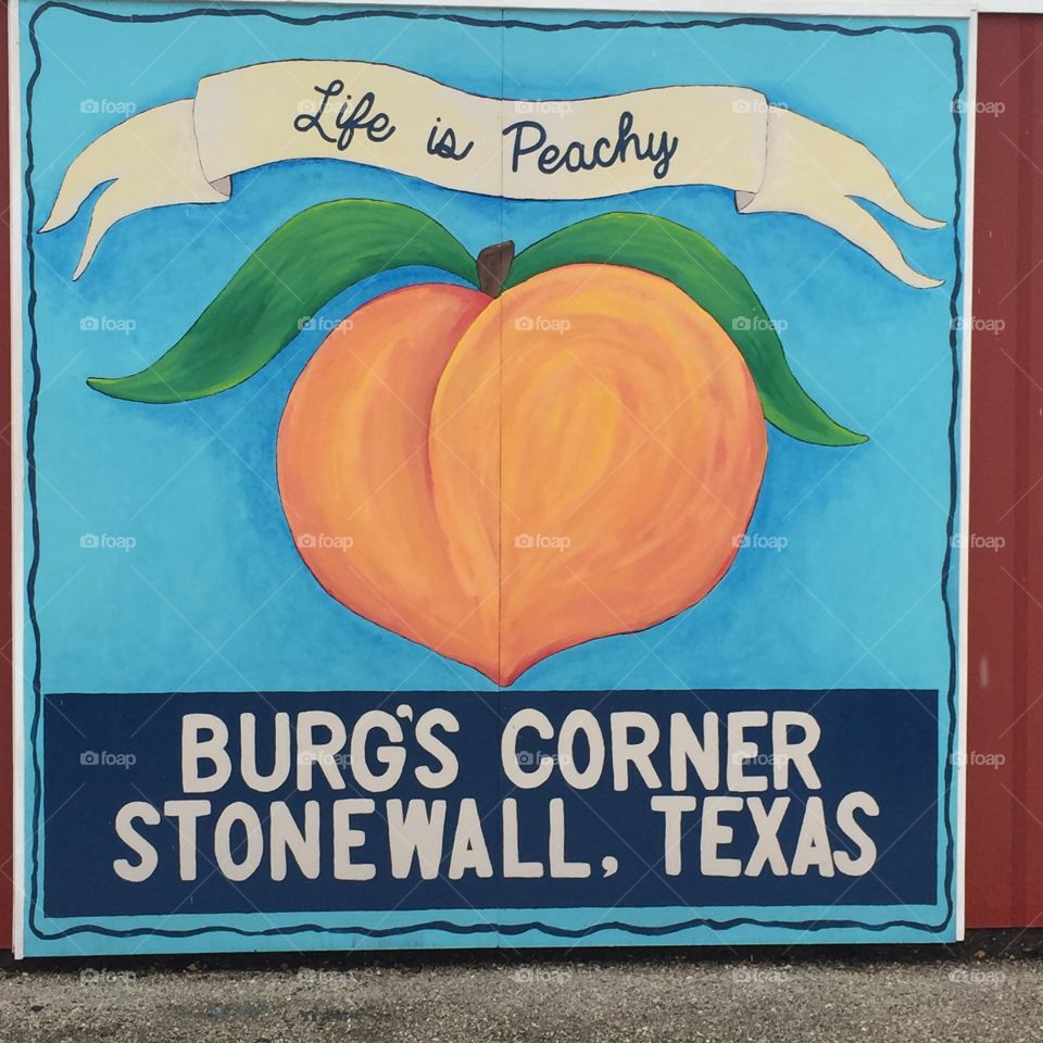 Painted sign on the side of a barn at Burg's Corner in Stonewall, Texas.