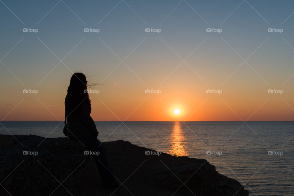 girl by the sea alone admires the sunset