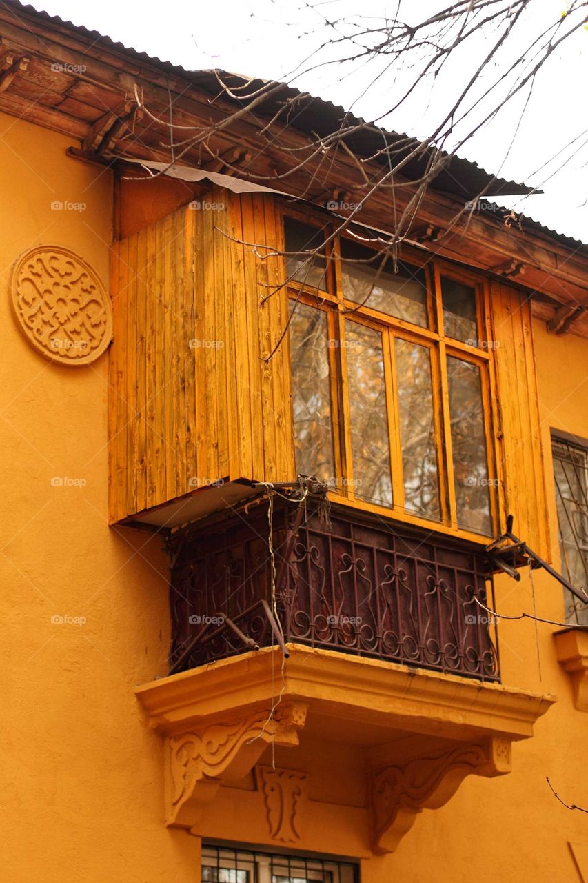 Balcony of an old yellow house on an autumn city street