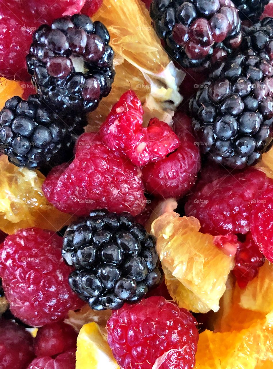 Imperfect summer fruit including raspberries, blackberries and oranges. 