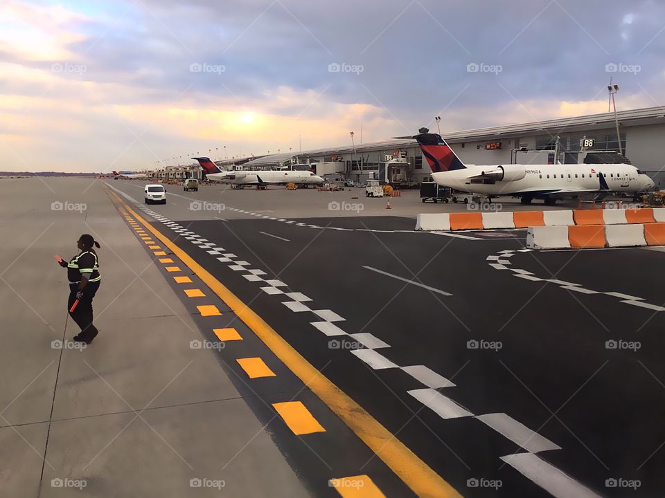 Airline traffic controller on the tarmac at sunset.