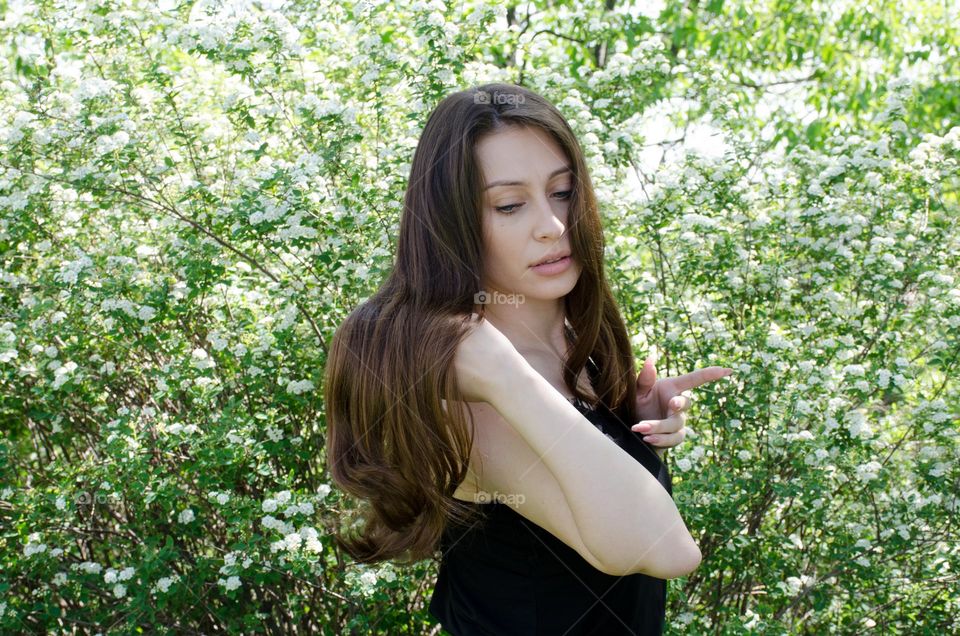 Woman brunette with beautiful natural hair on background of flowers