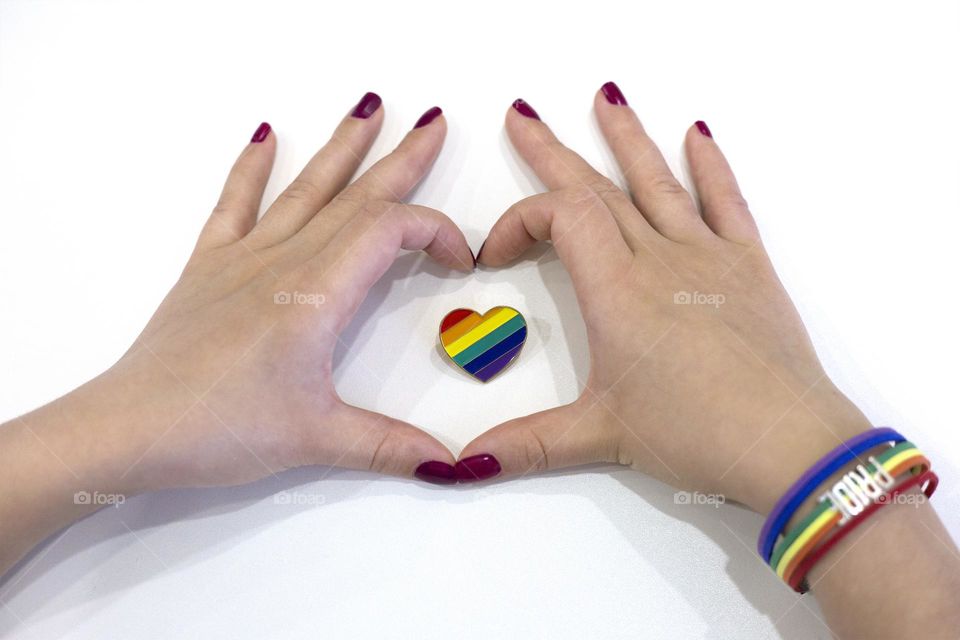 Hands in heart shape around the rainbow color heart. LGBT concept 