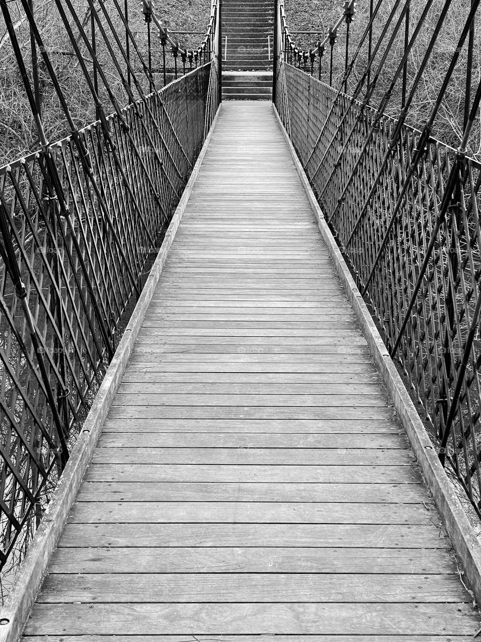 A footbridge across a creek connecting a park to a neighborhood