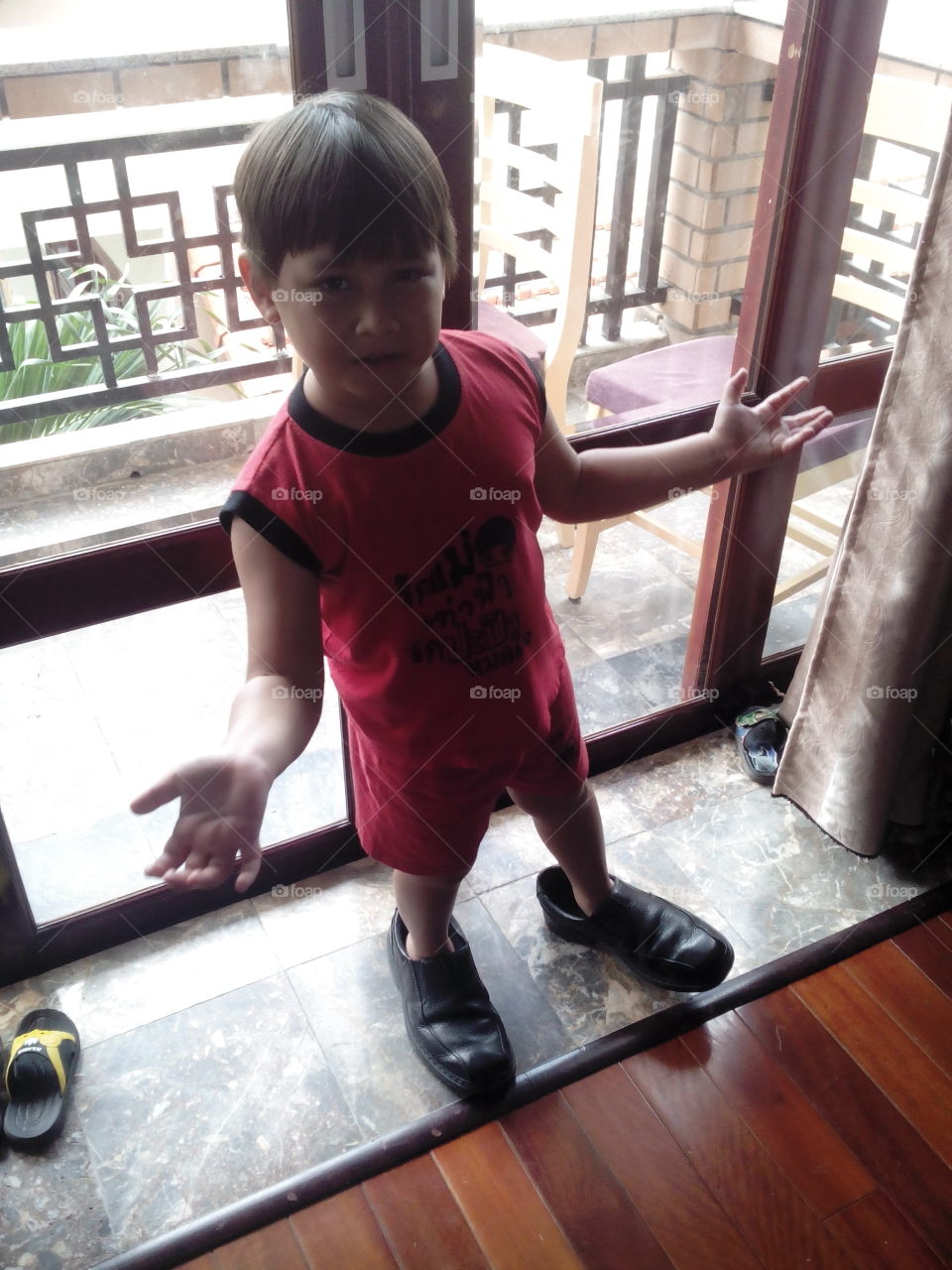 Funny kid with big shoes. boy wearing his dad shoes