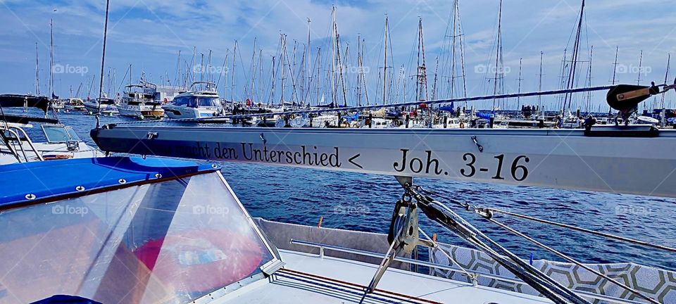Boats are lying ready to go on the shore of the „Baltic Sea“, the „Ostsee“ near „Rostock“ „Warnemünde“. The boat this photo was taken from has a Biblical inscription on the  „boom“ that is designed to hold a sail. 2023. Hypnotic Productions
