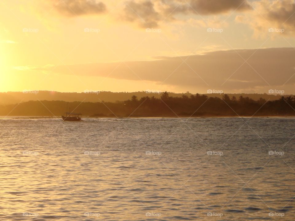 Sunset in Itacaré . A boat passes by as the sun goes down in Itacaré beach, Bahia, Brazil 